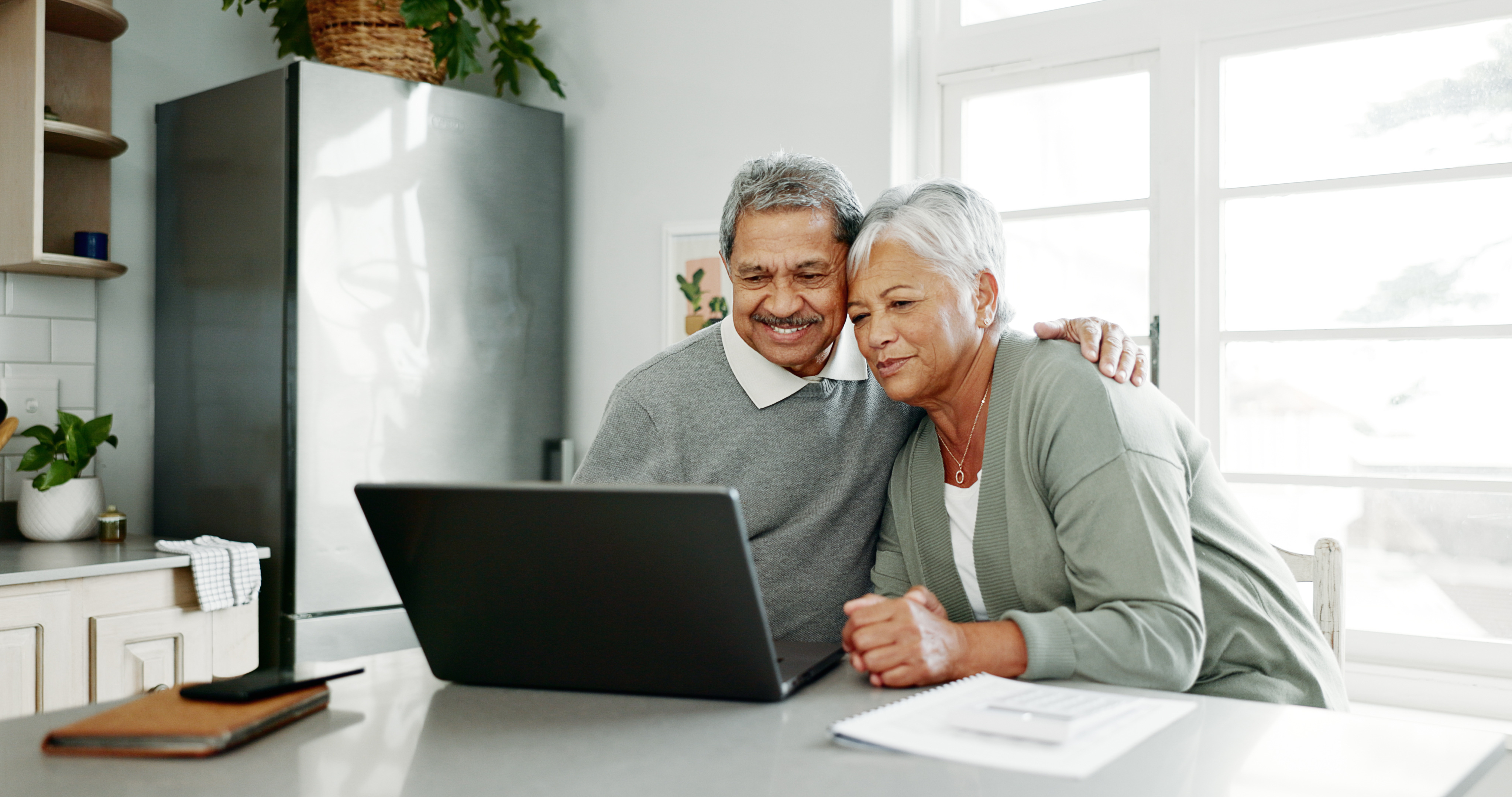 Practical Estate Planning Services A senior couple happily reviewing estate planning documents and a laptop together.